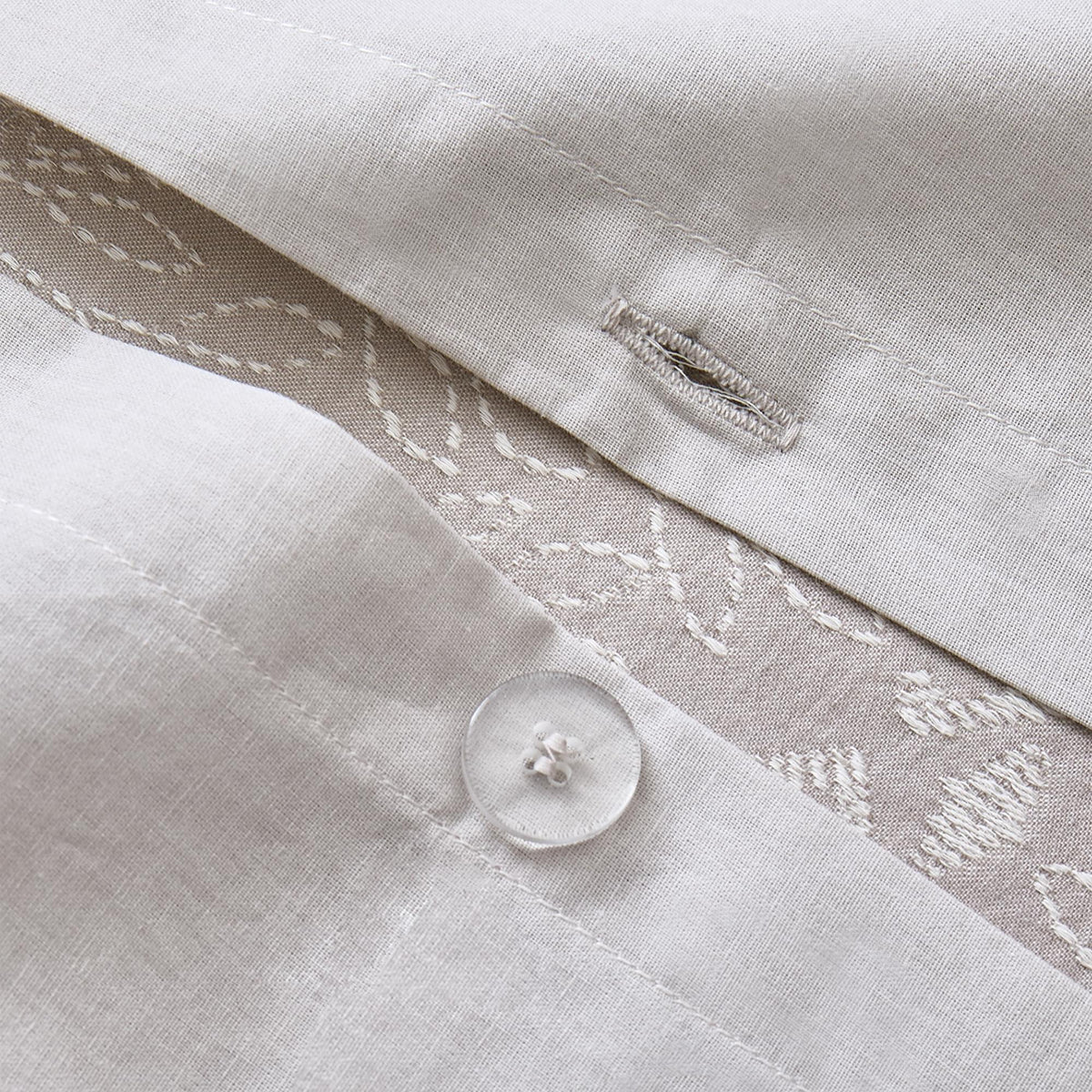 Close-up of a light gray Timeless Heritage Woven Duvet Cover Set with embroidered details and a button.