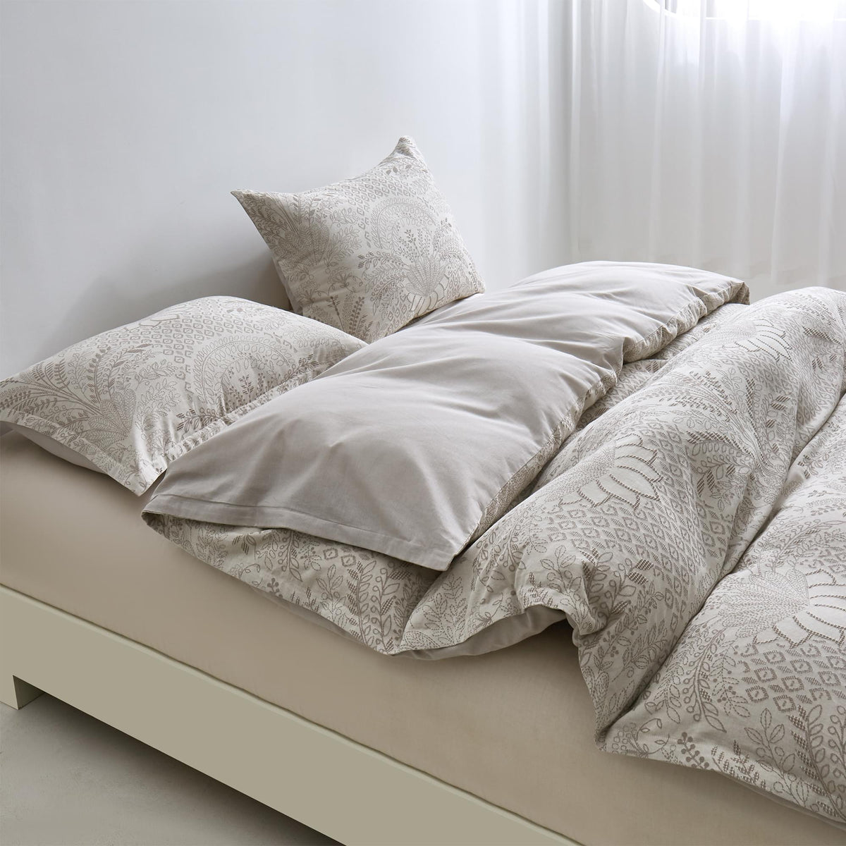 Neatly made bed with Timeless Heritage Woven Comforter Set and pillows in a bright room.