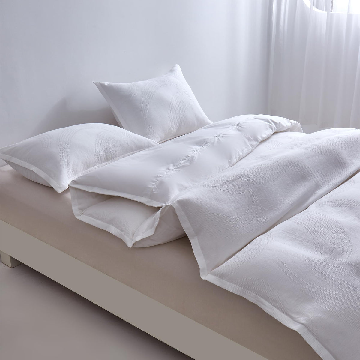 White Aurora Bloom Leaf Jacquard Duvet Cover Set White on a bed with light-colored walls and floor.