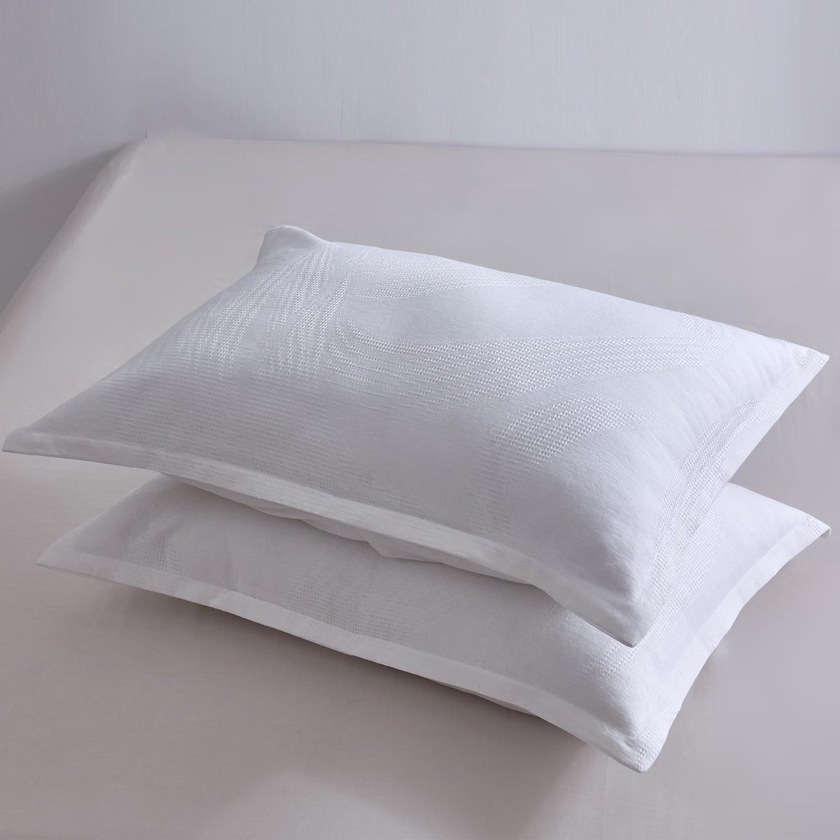 Two white pillows on a light gray surface with a plain background
