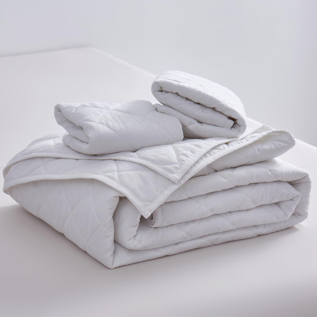 Folded white comforter on a light gray surface