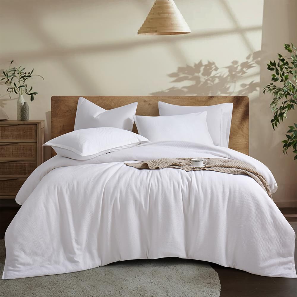 Neatly made bed with white Aurora Bloom Leaf Jacquard Duvet Cover Set White and pillows in a bedroom setting.