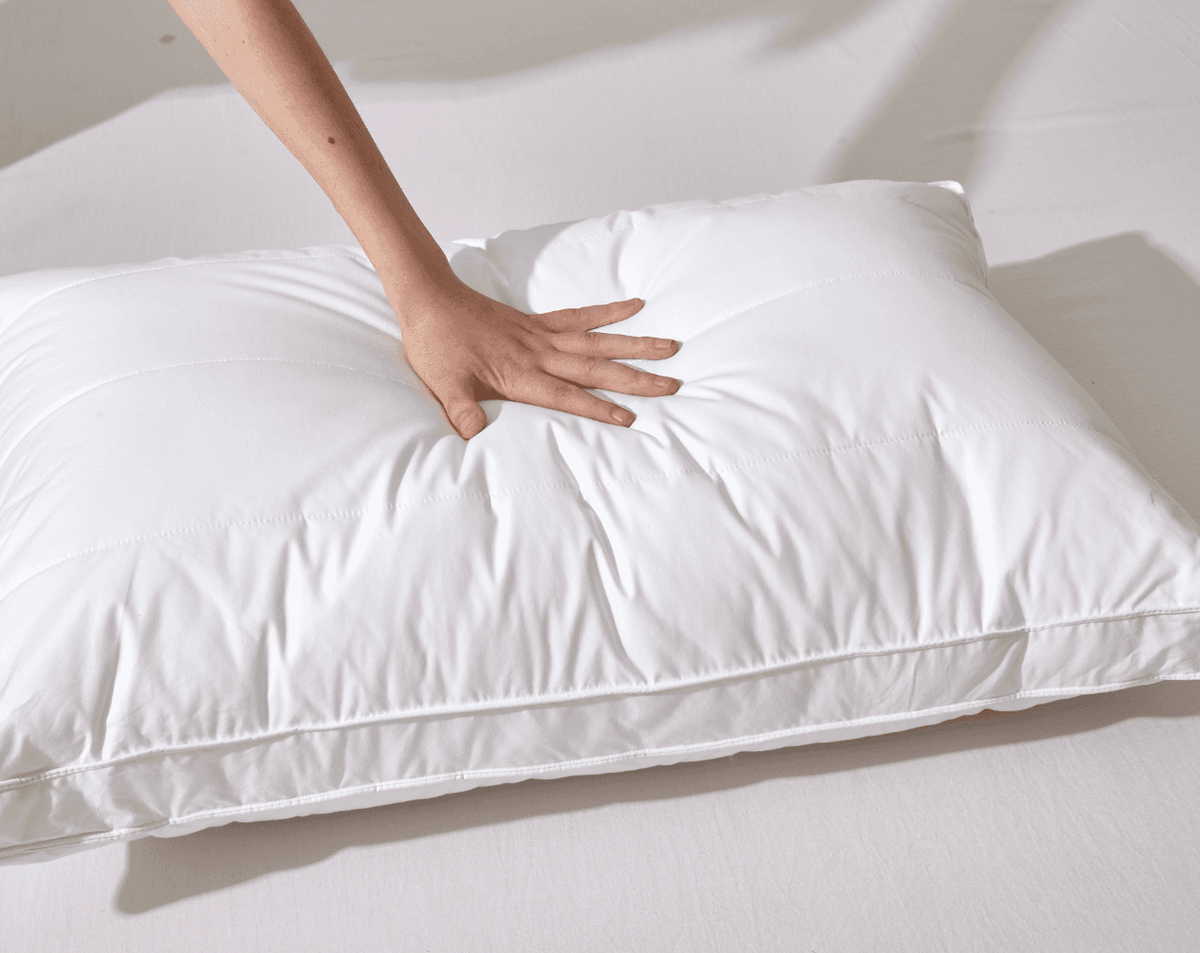 White Organic Cotton White Pillow on a bed with a hand touching it