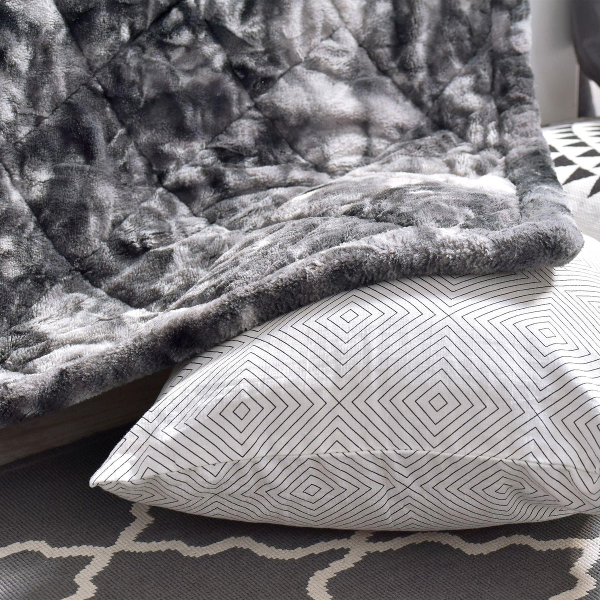 Gray textured Hug Me Faux Weighted Throw Blanket draped over a surface with a geometric-patterned pillow underneath.