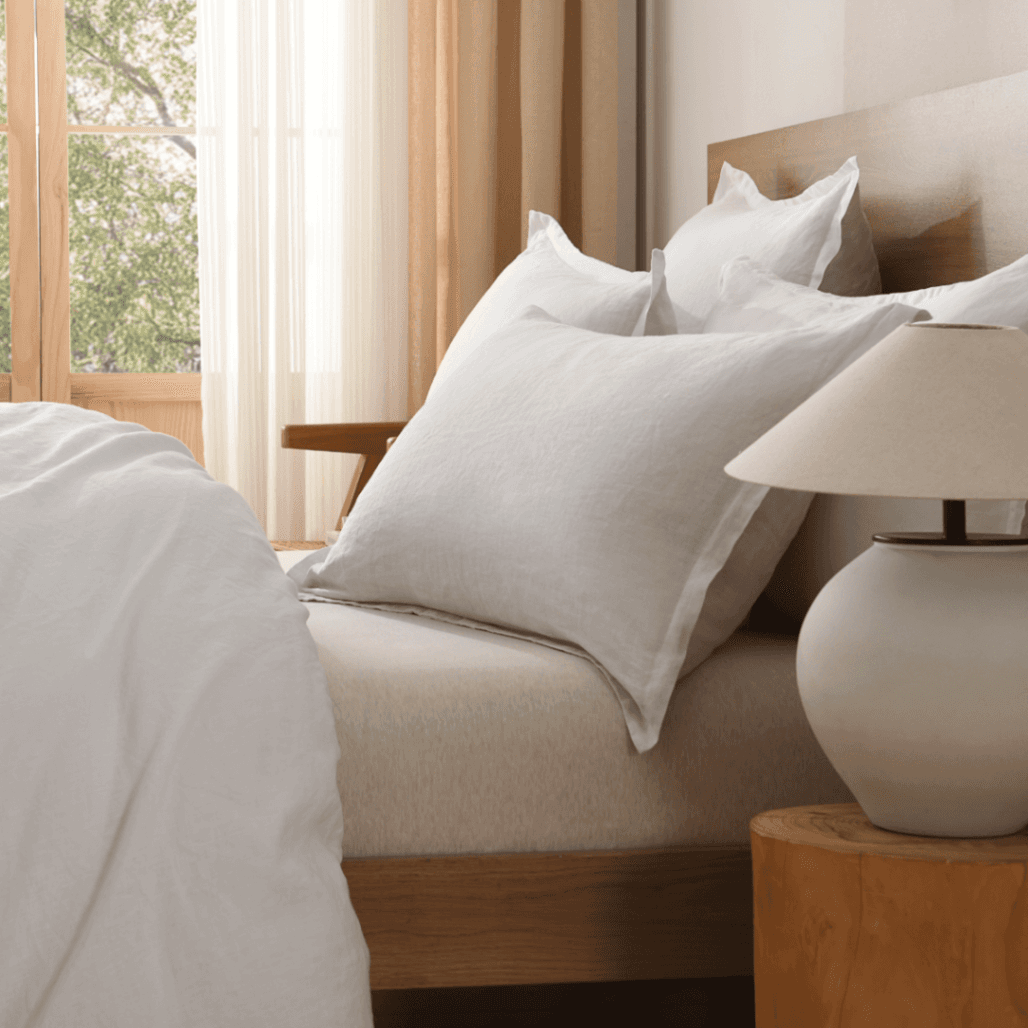 Neatly made bed with pillows and a lamp on a nightstand in a bedroom.