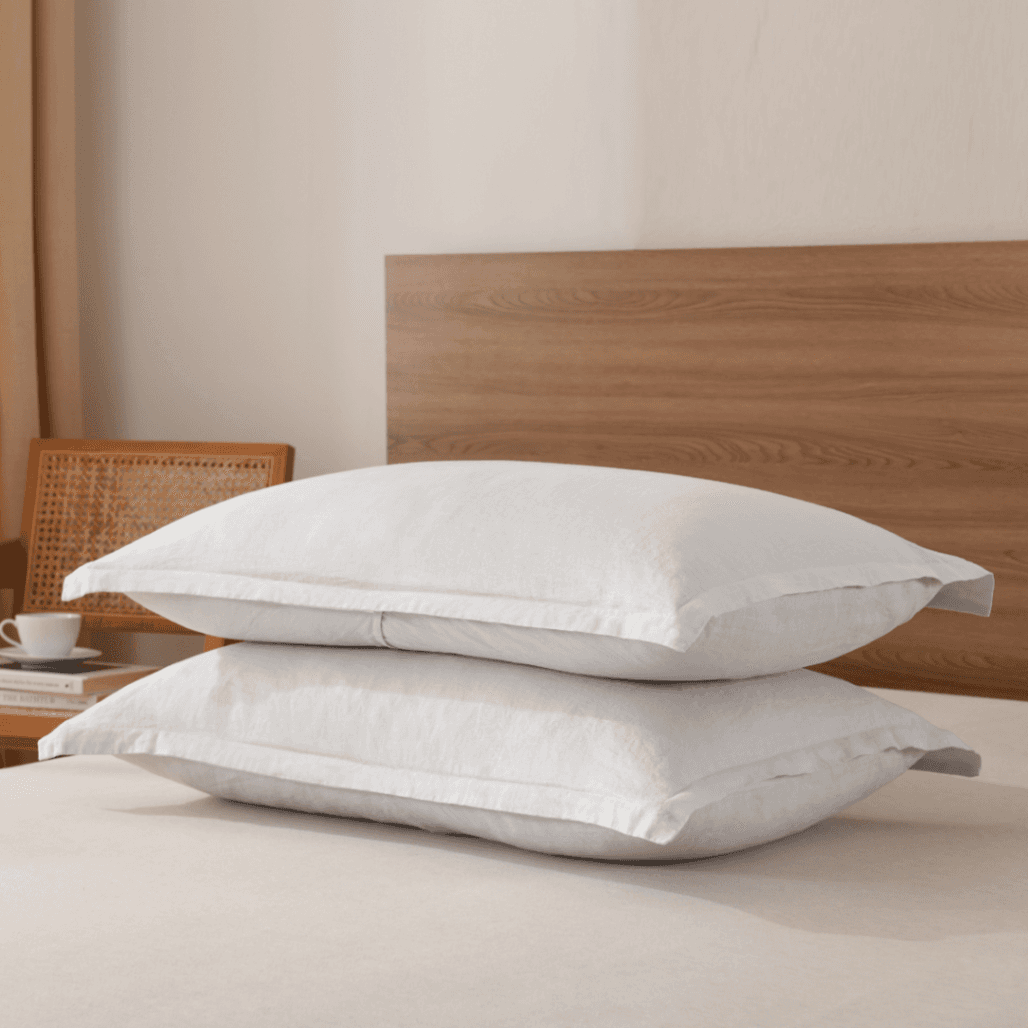 Two white pillows on a bed with a wooden headboard.