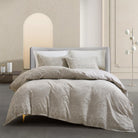 Neatly made bed with beige Timeless Heritage Woven Comforter Set and pillows in a modern bedroom setting.