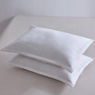 Two white pillows on a light gray surface with a plain background