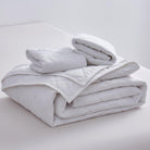 Folded white comforter on a light gray surface