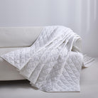 White Timeless Heritage Woven Quilt Set White blanket draped over a white sofa against a light gray background