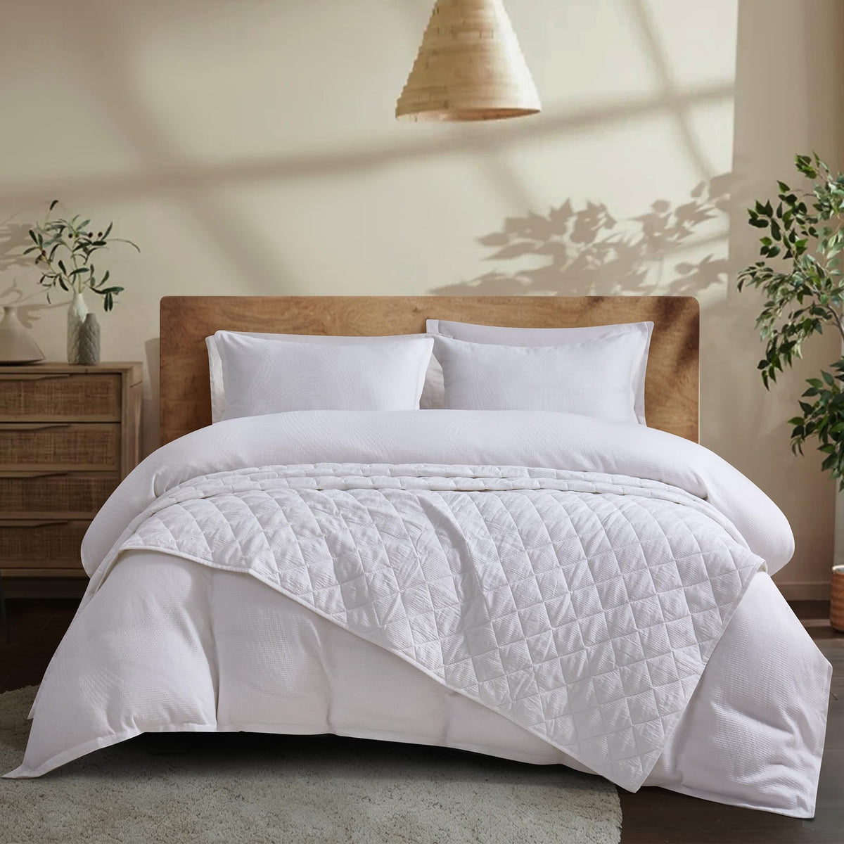 White Aurora Bloom Leaf Jacquard Quilt Set White on a bed in a bedroom setting with wooden headboard and side tables.