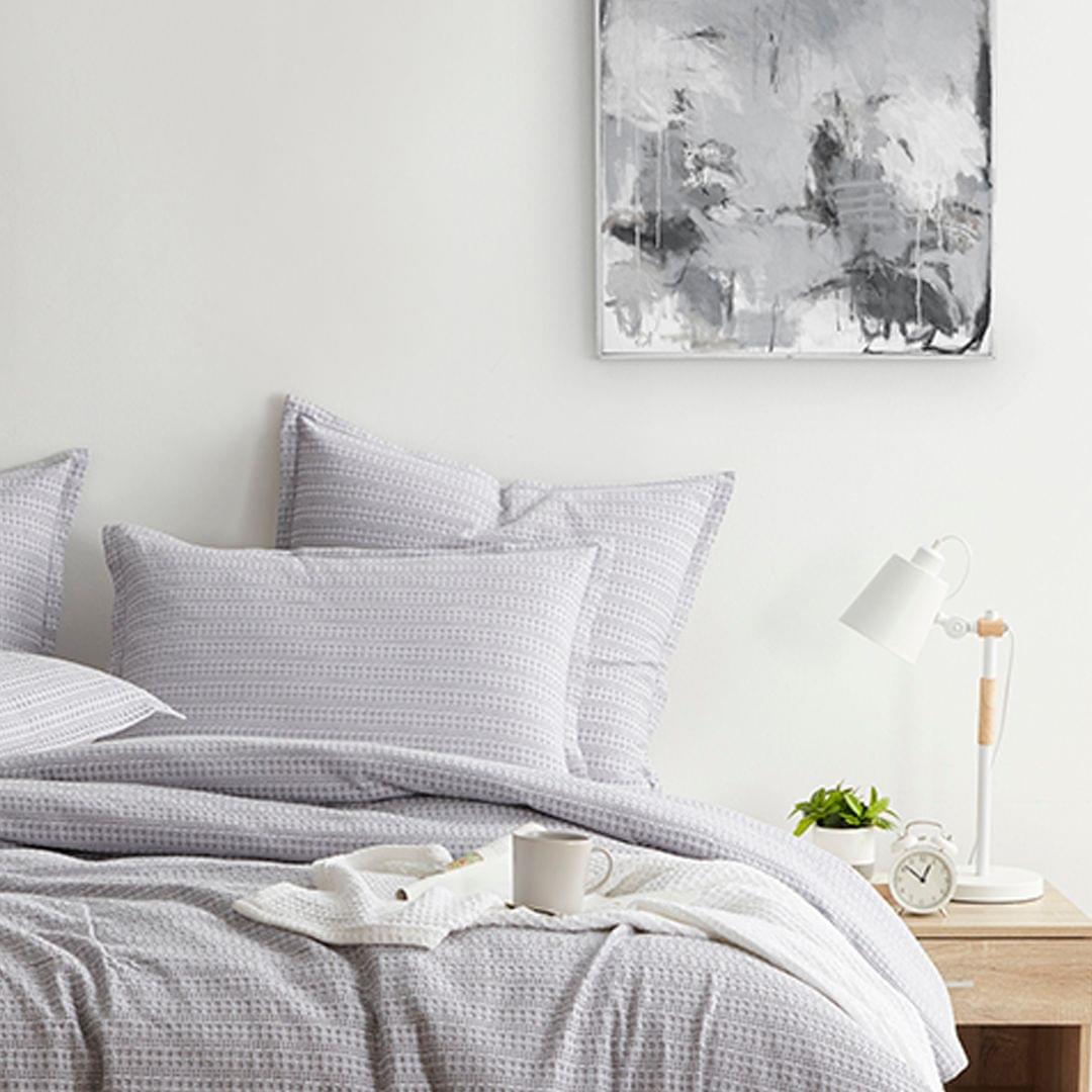 Neatly made bed with light gray Seersucker Euro Sham in a bedroom setting.