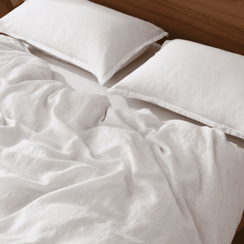 White comforter and pillows on a bed with wooden headboard