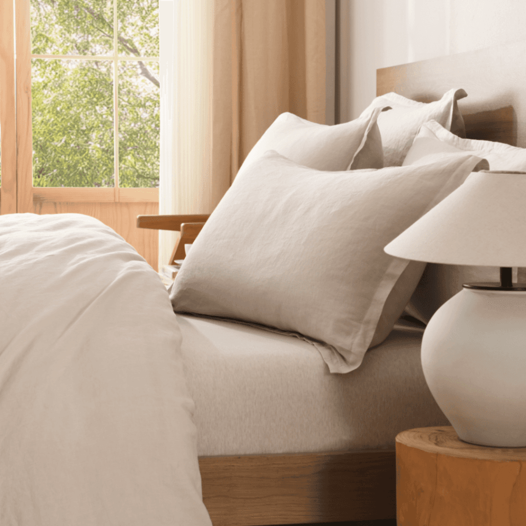 Neatly made bed with beige European Flax Linen Duvet Cover and pillows in a bright bedroom.