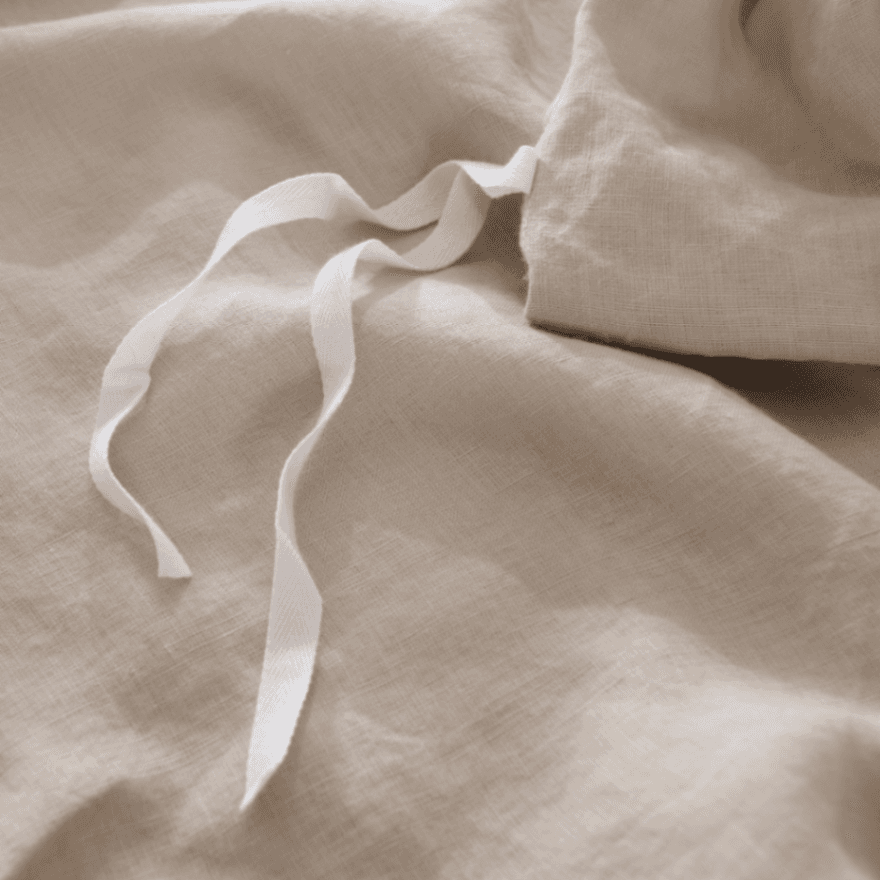 Beige European Flax Linen Duvet Cover fabric with a white ribbon on a beige background
