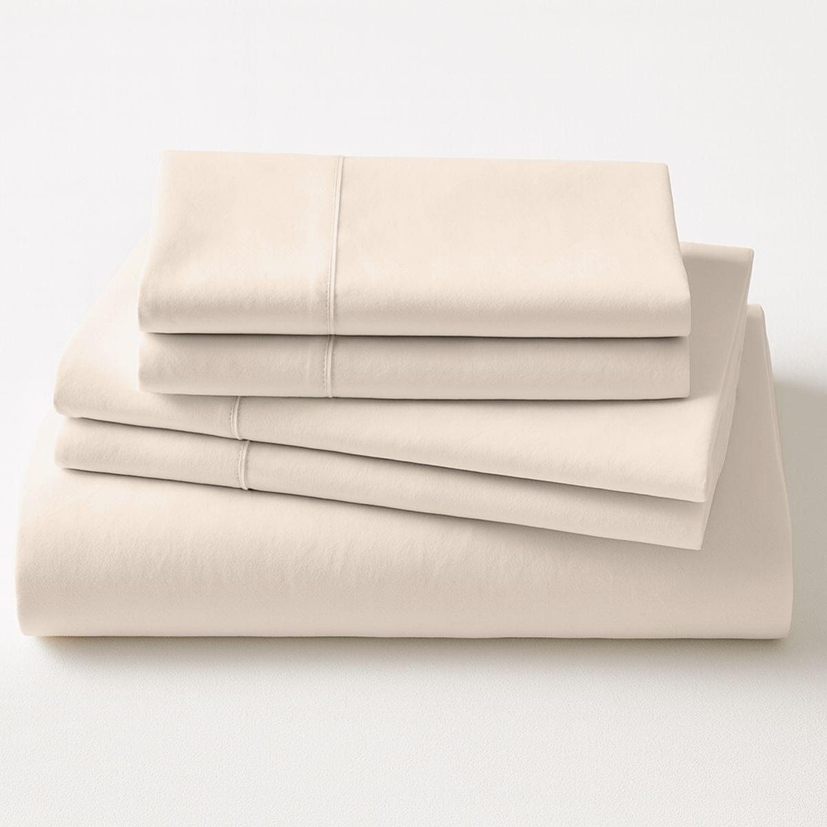 Folded beige bed sheets on a white background