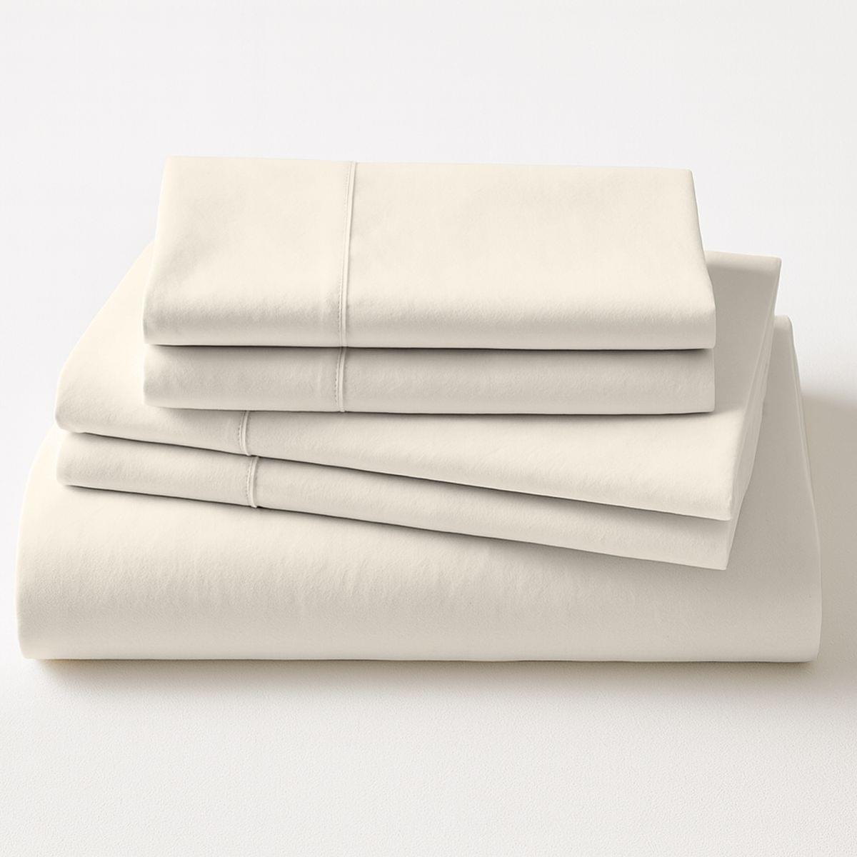 Folded beige bed sheets on a white background