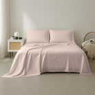 Pink Organic Cotton Sheet Set 400 Thread Count and pillows on a bed in a minimalistic room.