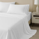 White Organic Cotton Sheet Set 400 Thread Count and pillows on a neatly made bed with a nightstand and lamp in the background.
