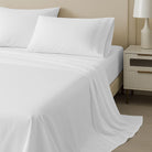 White 100% Cotton Sheet Set 400 Thread Count and pillows on a neatly made bed with a nightstand and lamp in the background.