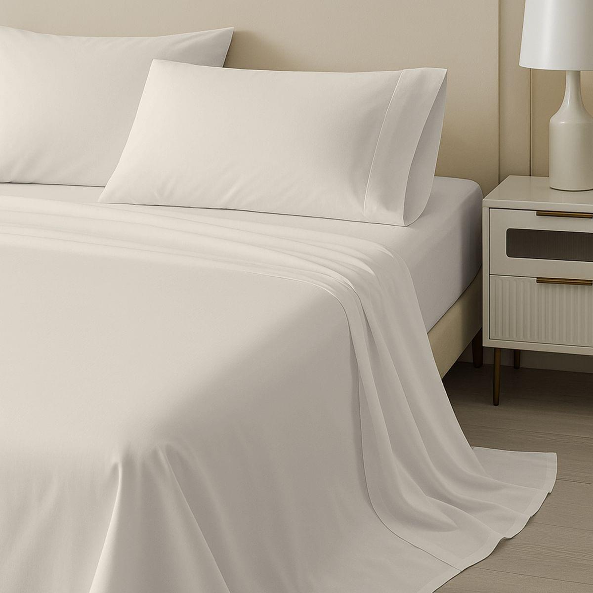 Neatly made bed with light pink bedding and pillows in a bedroom setting.