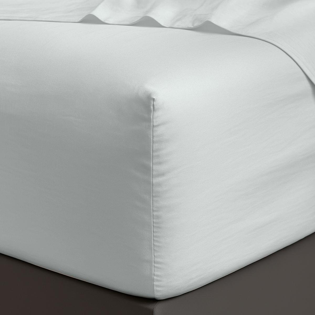 White satin sheet corner on a bed with a dark surface