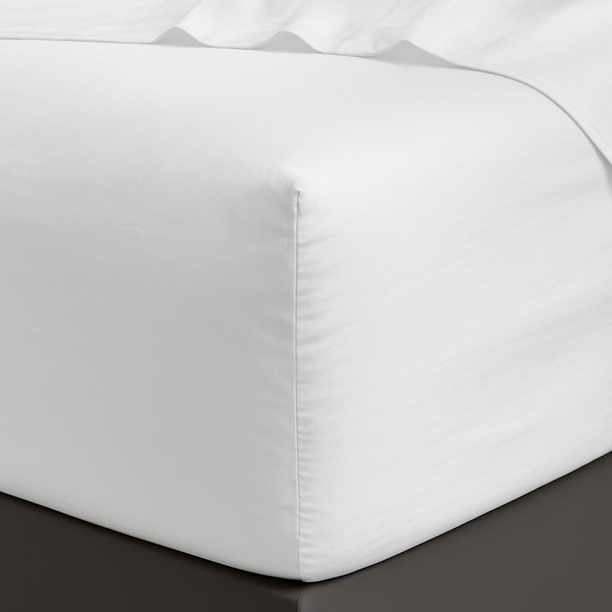 White fitted sheet on a bed corner with a plain background