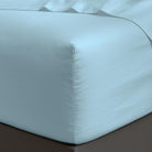 Close-up of a fitted sheet on a bed with a neutral color scheme.
