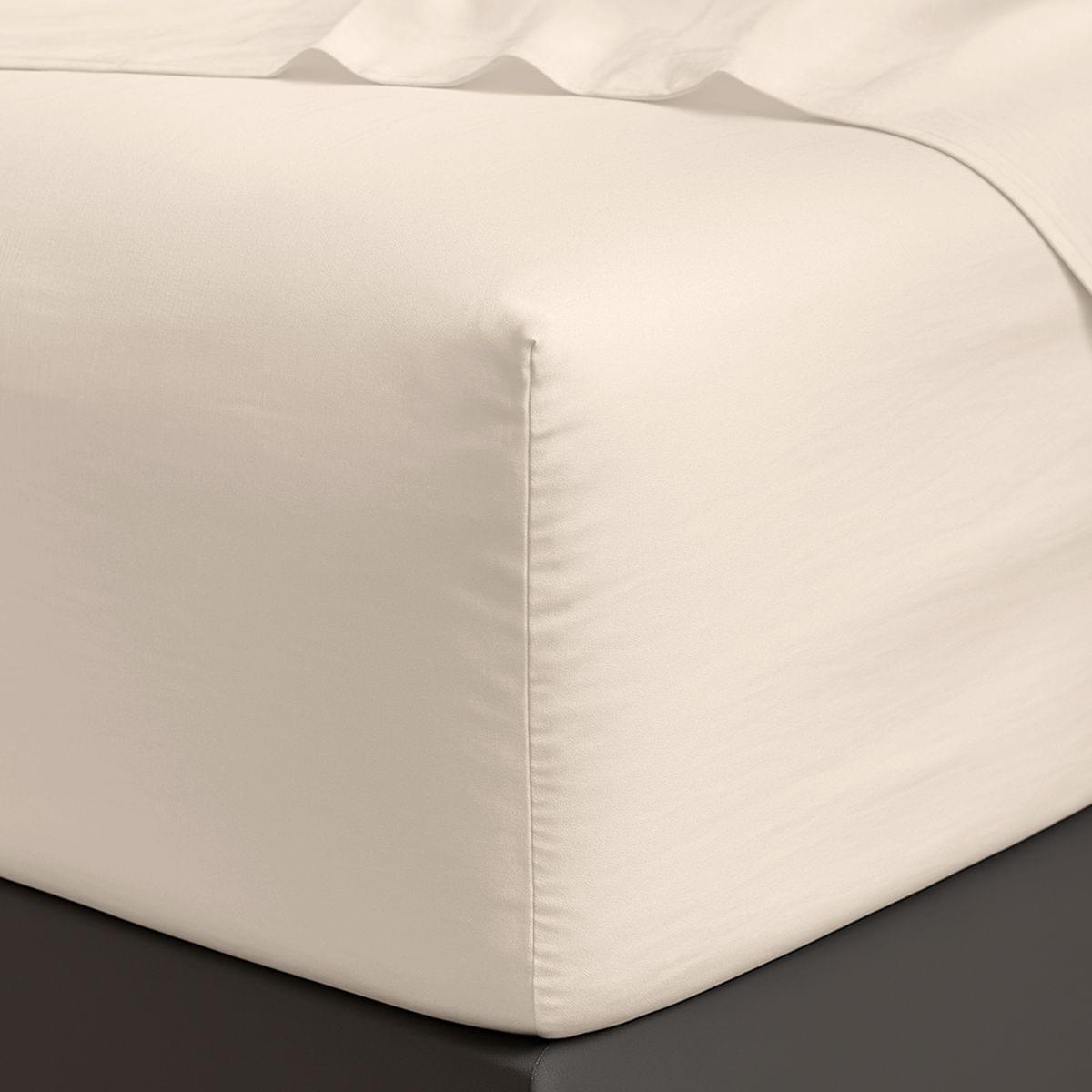 Close-up of a fitted sheet on a bed with a neutral background