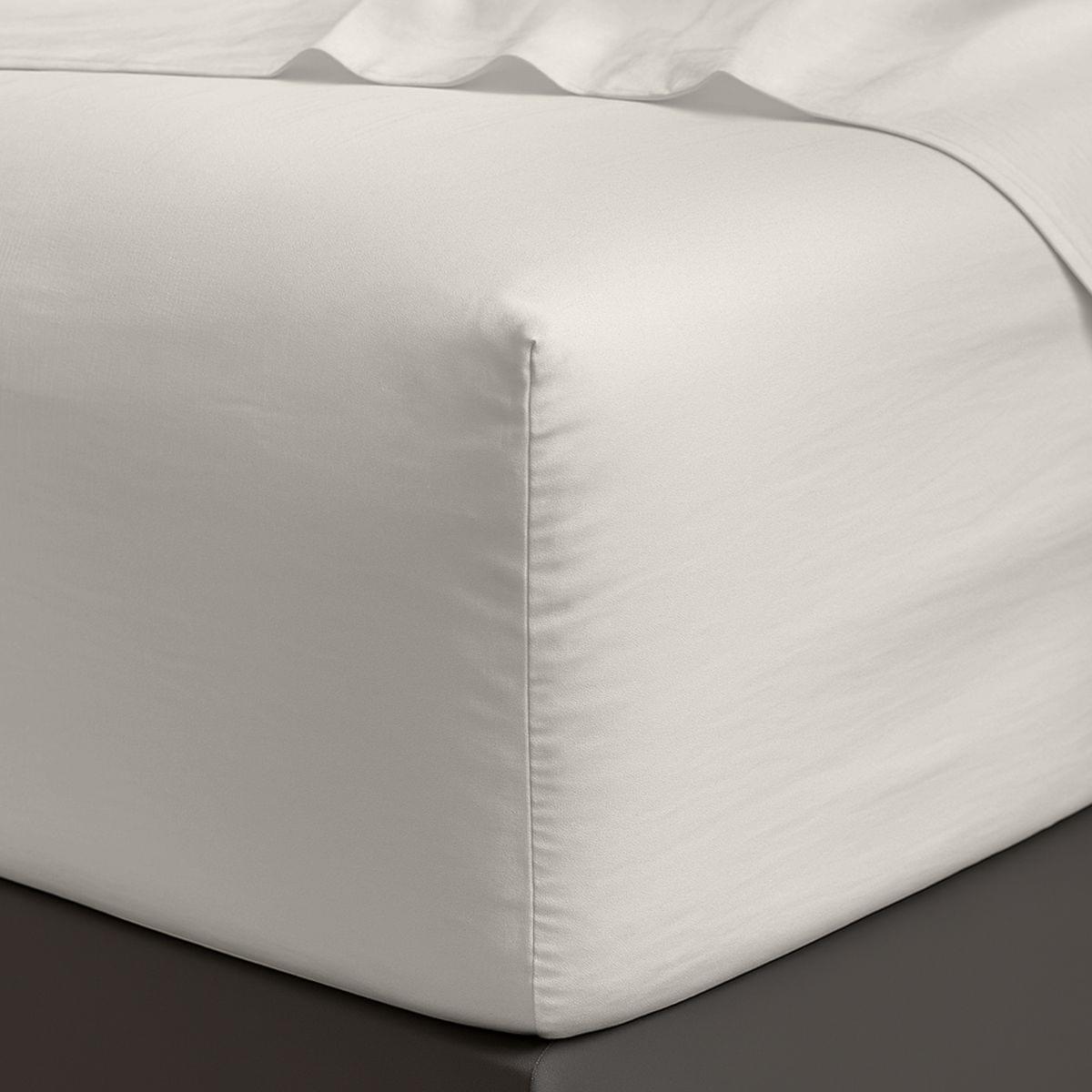 White satin sheet corner on a bed with a dark surface