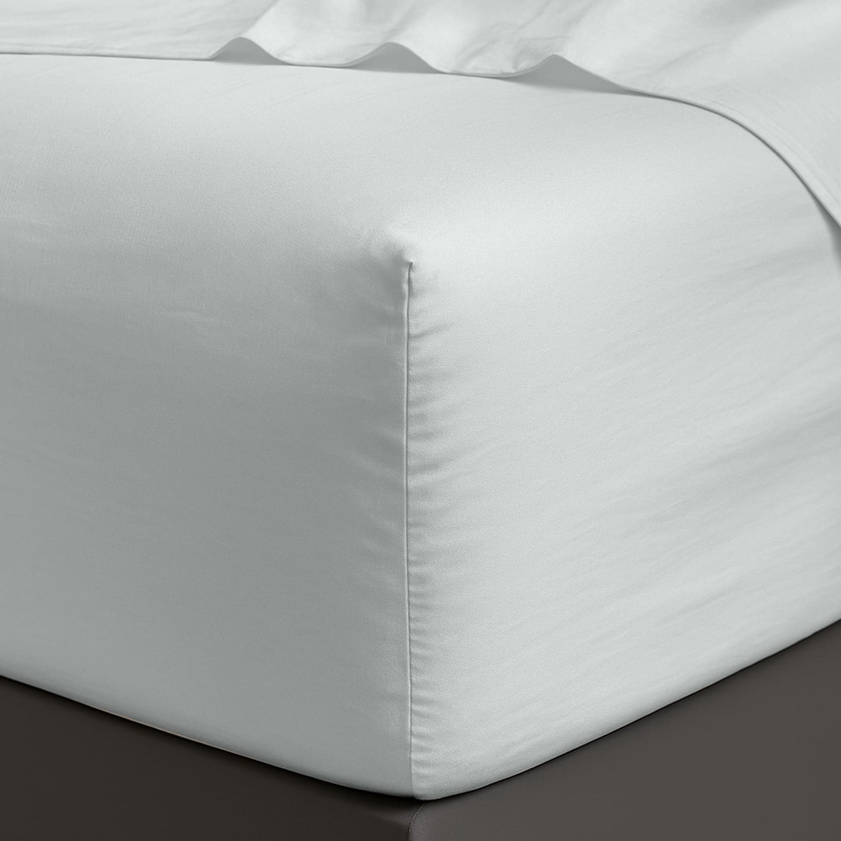 White satin Organic Cotton Sheet Set 400 Thread Count corner on a bed with a dark surface