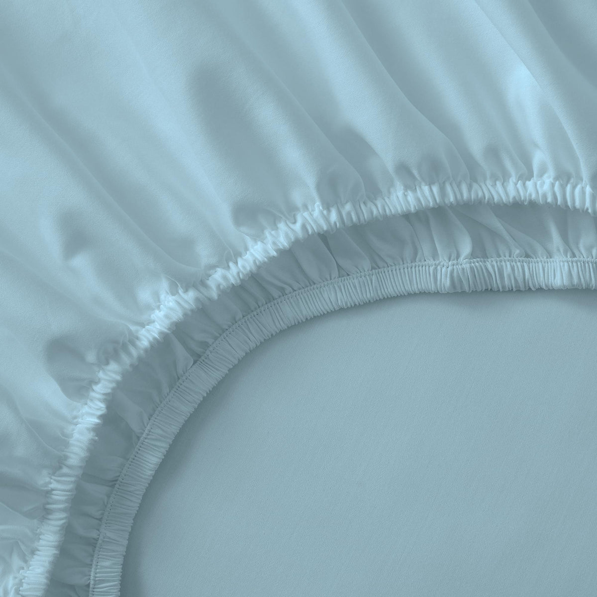 Close-up of a light blue fitted sheet with a plain background
