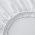Close-up of a white fitted sheet on a bed
