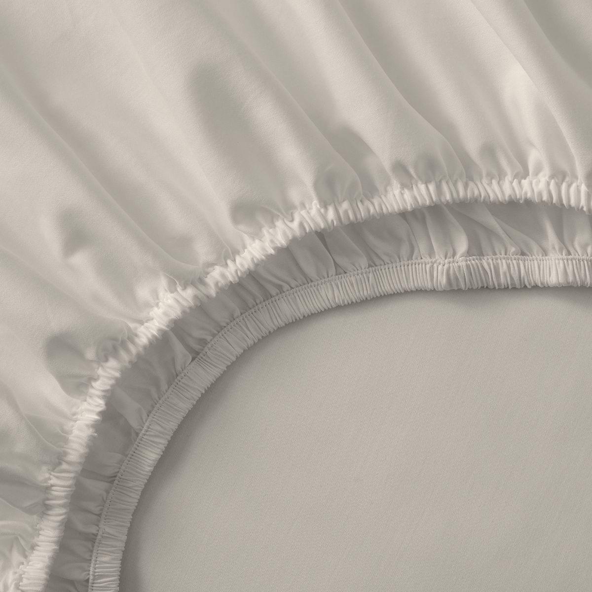 Close-up of a fitted sheet with ruffled edge on a bed.