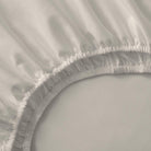 Close-up of a fitted sheet with ruffled edge on a bed.