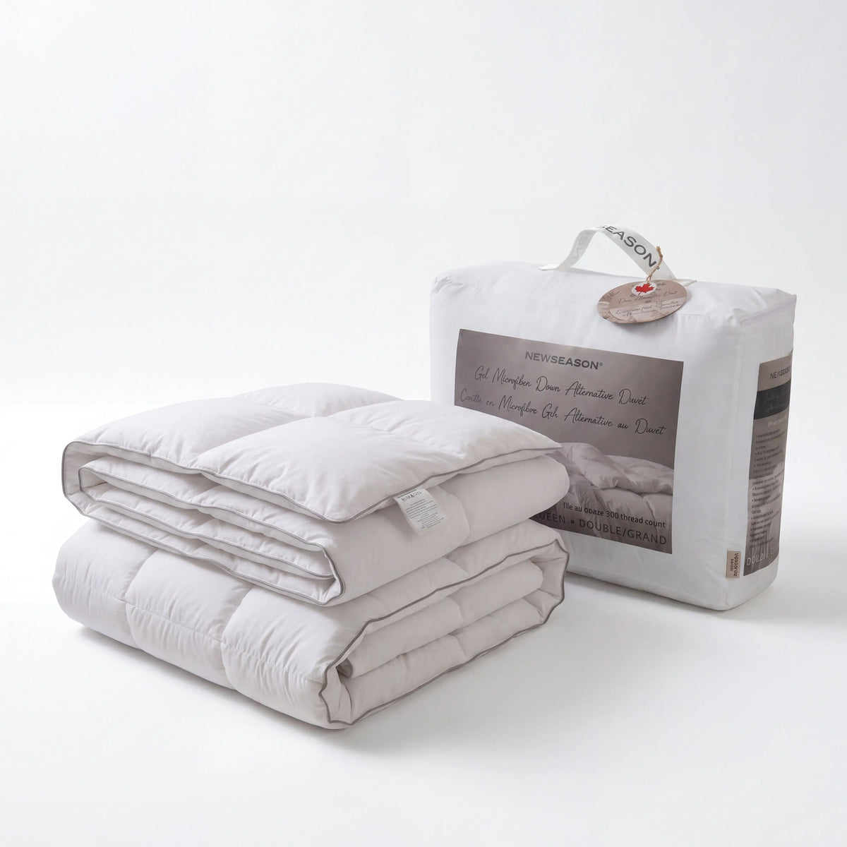 A folded quilted Down Alternative Gel Microfiber Duvet in a light warm gray or off-white tone stands in front of its white branded packaging bag. The packaging shows the text 'NEWCLASON' and 'Gel Hypothermia Queen Protection Layer.