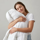 Woman hugging a large white Down and Feather Duvet  against a plain background