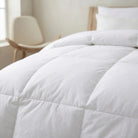 Close-up of a white Down and Feather Duvet on a bed in a softly lit bedroom.