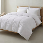 White Down and Feather Duvet and pillows on a wooden bed in a minimalistic bedroom.