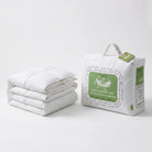A folded white quilted Down and Feather Duvet sits beside its white retail packaging with green labels on a clean white studio background.