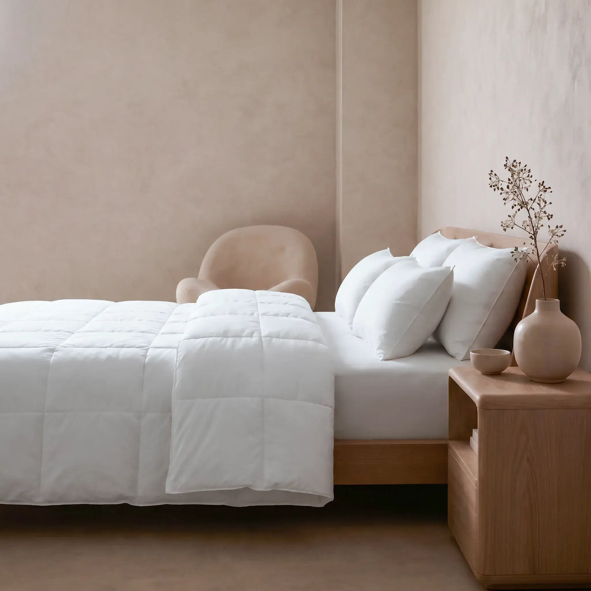 Neatly made bed with white Down and Feather Products Duvet and pillows in a bedroom setting.