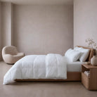 Neatly made bed with white Down and Feather Products Duvet in a minimalistic bedroom setting.