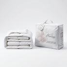 Folded white Down and Feather Products Duvet next to its packaging on a light gray background