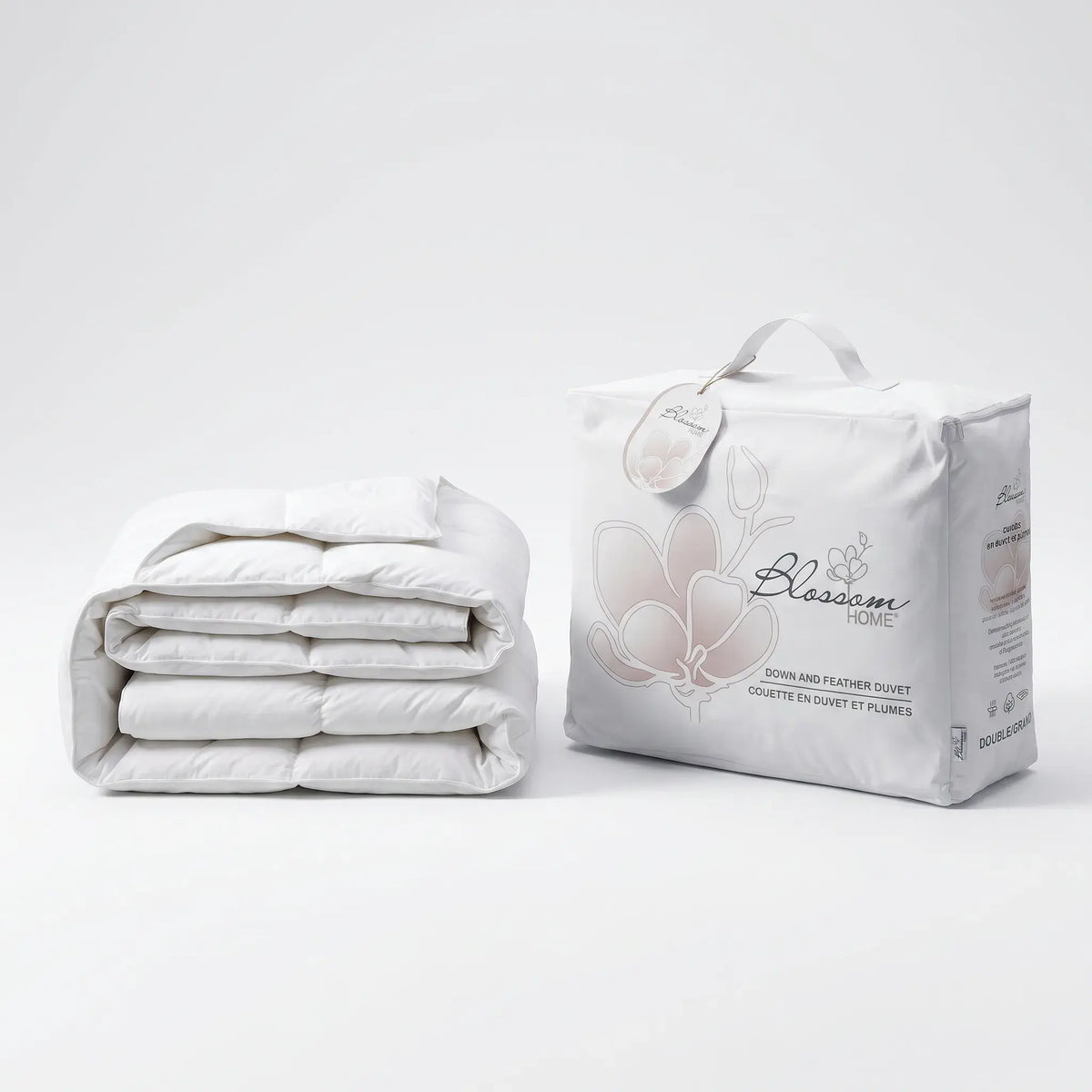 Folded white Down and Feather Products Duvet next to its packaging on a light gray background