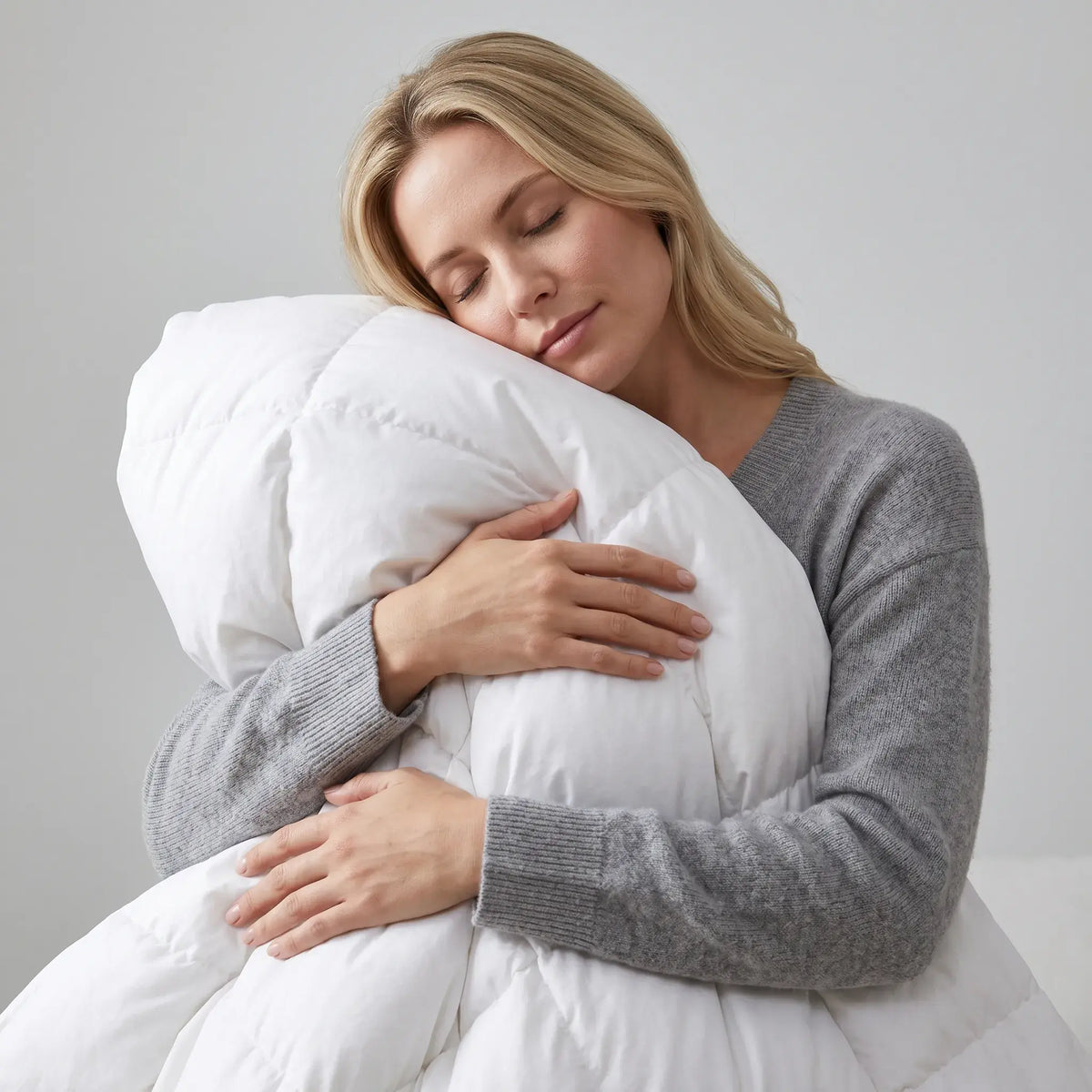 Woman embracing a large white Down and Feather Products Duvet against a plain background