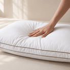 Hand touching a white Down Alternative Gel Microfiber Pillow on a beige surface