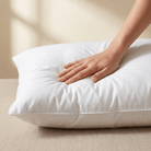 Hand resting on a white Down and Feather Pillow against a beige background