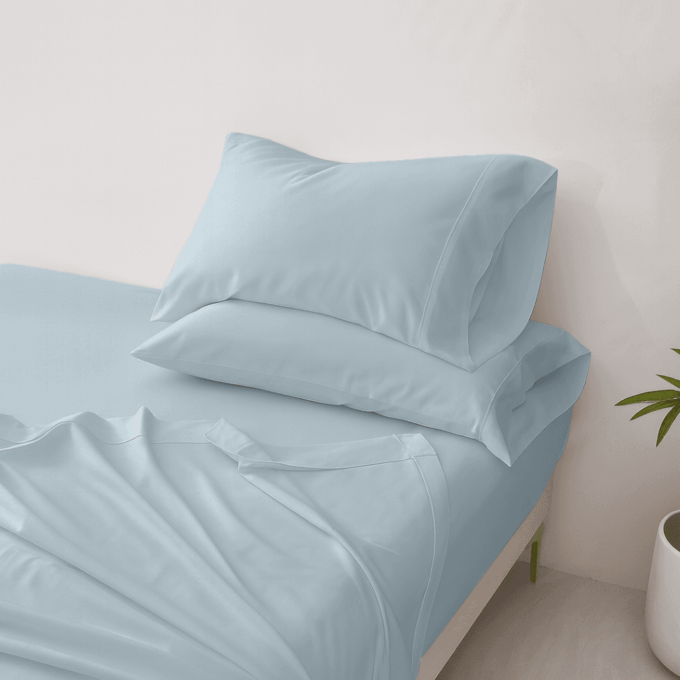 Light blue bedding set with a pillow on a bed against a neutral wall.