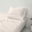 White Organic Cotton Sheet Set 500 Thread Count set with pillows on a bed in a minimalistic room.