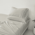 Gray bedding set with pillows on a bed in a minimalistic room.